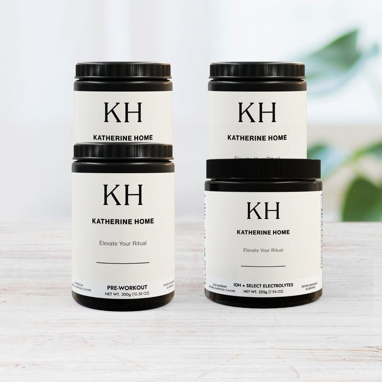 Katherine Home premium supplement jars, including Pre-Workout and Electrolyte formulas, displayed on a light wooden surface.