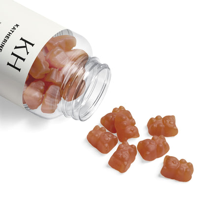 Open bottle with collagen gummies spilled on a white surface, showcasing shape and soft texture.